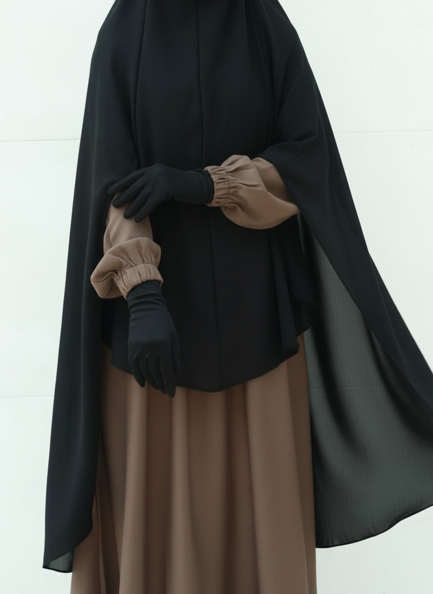 Person wearing a black cloak over a brown dress with gloves on a white background