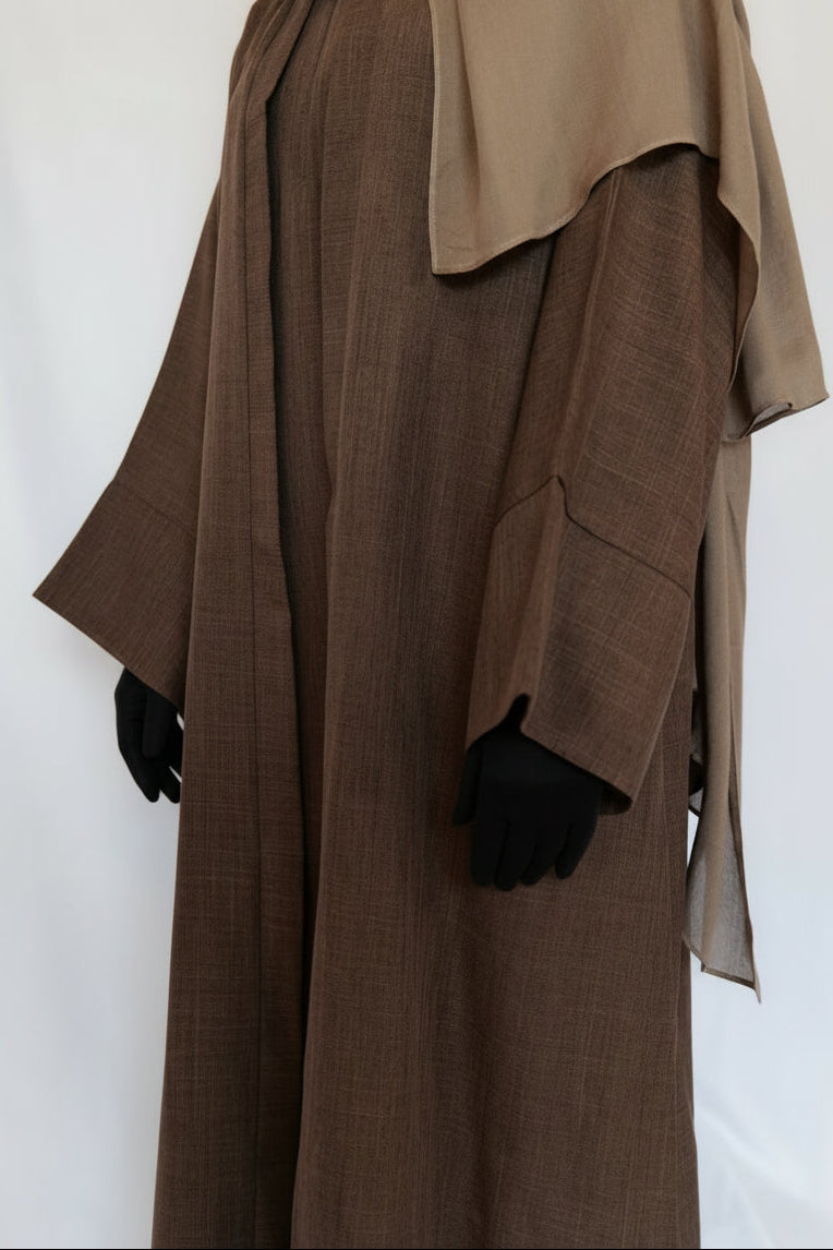Person wearing a brown abaya with a matching headscarf on a white background