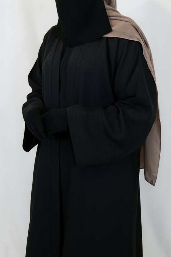 Person wearing a black abaya with a brown hijab on a white background