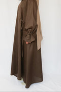 Person wearing a brown abaya with a matching hijab on a white background
