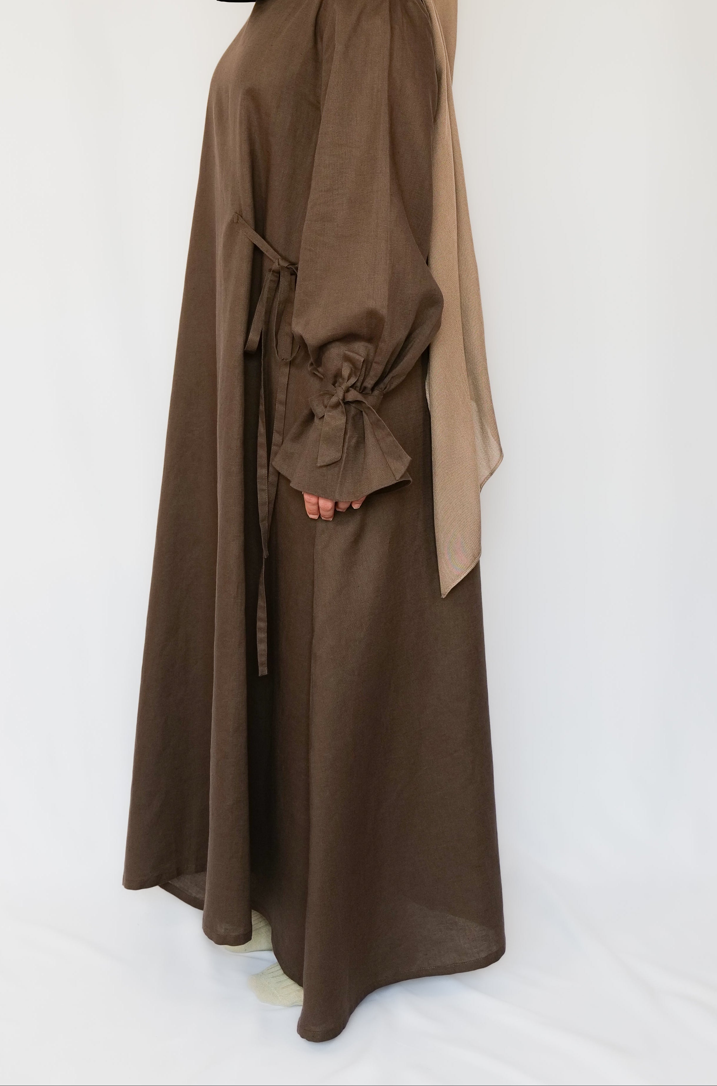Person wearing a brown abaya with a matching hijab on a white background