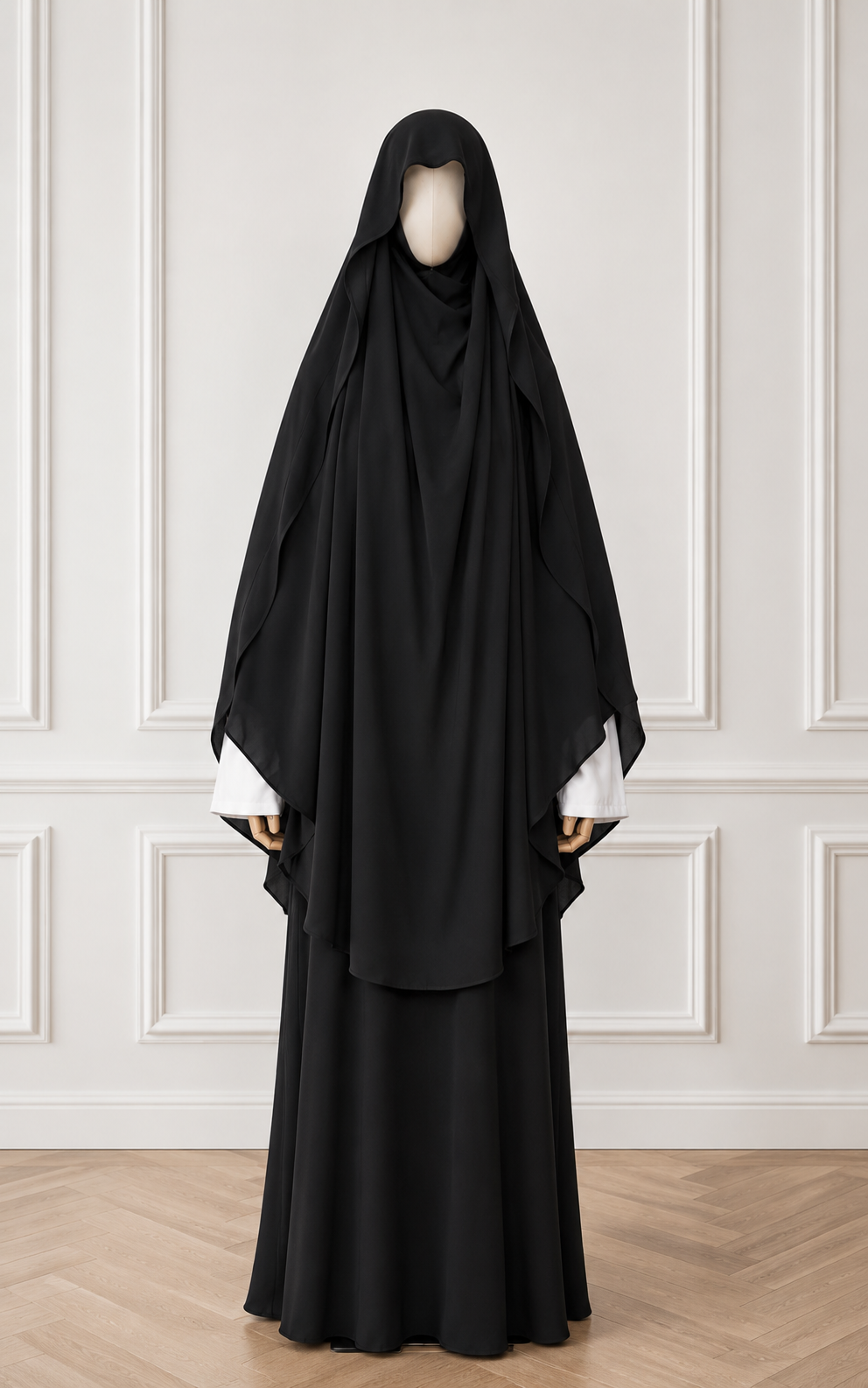 Black abaya worn by a mannequin against a white paneled wall.